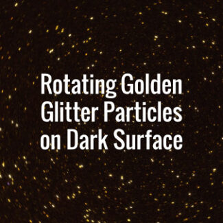 Seamlessly looping spinning flickering golden glitter particles on black surface.