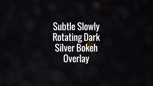 Seamlessly looping subtle slowly rotating dark silver bokeh particles on black background.