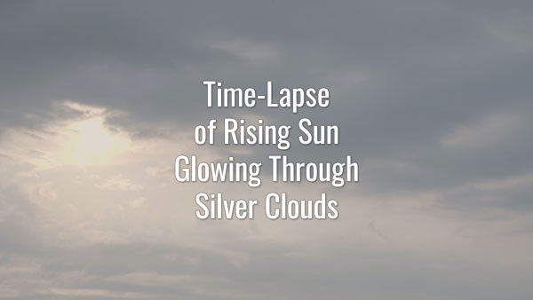 Time-lapse video of rising sun seeing through fast-moving gray clouds